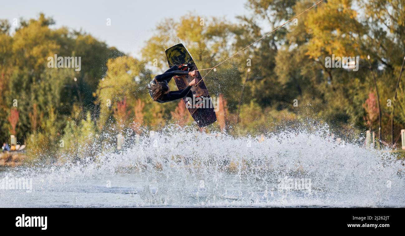 Wakeboarder making tricks while wakeboarding on lake. Young man surfer having fun wakesurfing in