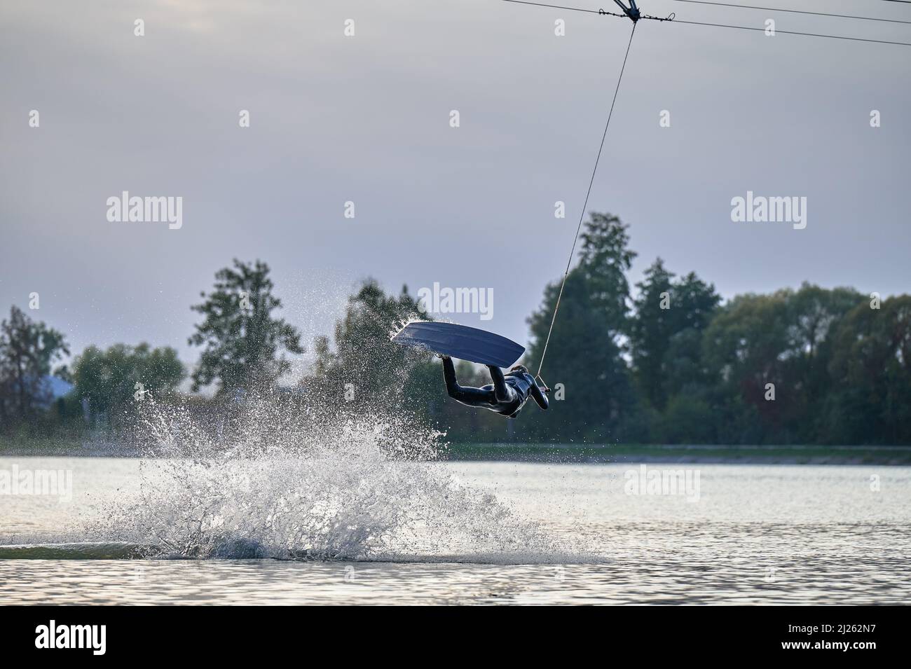 Wakeboarder making tricks while wakeboarding on lake. Young man surfer having fun wakesurfing in