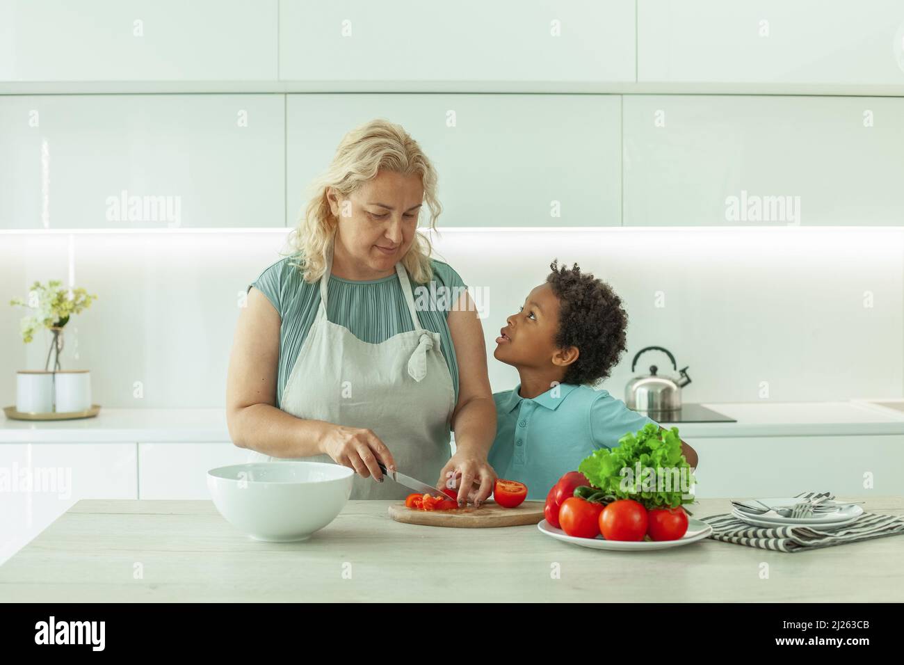 Curious nosy child with his mother indoors in kitchen Stock Photo