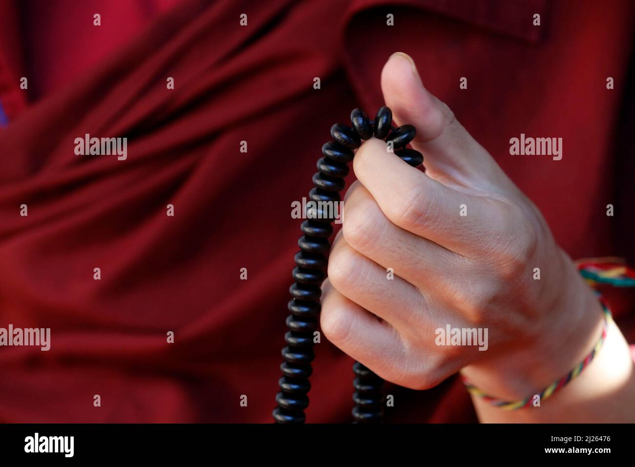 Pema Osel Ling Monastery. Hand of a monk praying and counting beads at