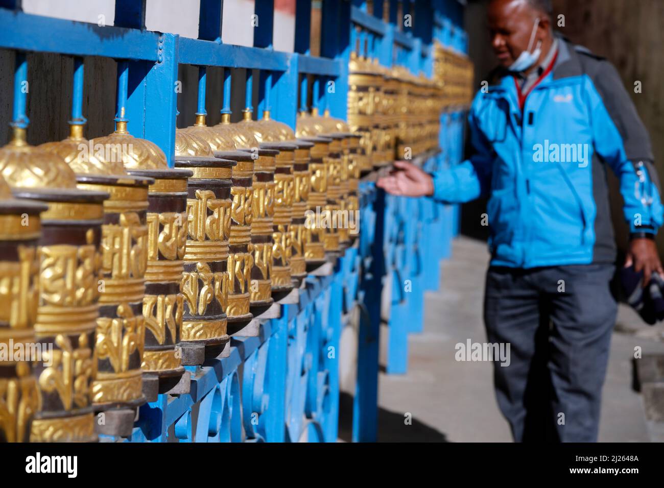 Shakhya Tharig Buddhist Monastery.  Rolling metal prayer wheels circling.  A mantra is written in Tibetan language, on the outside of the wheel. Stock Photo