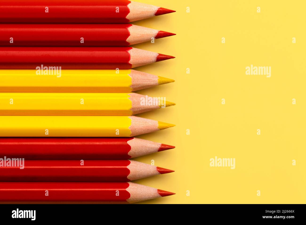 Top view of Spain flag made with red and yellow colored pencils with copy space over yellow background Stock Photo