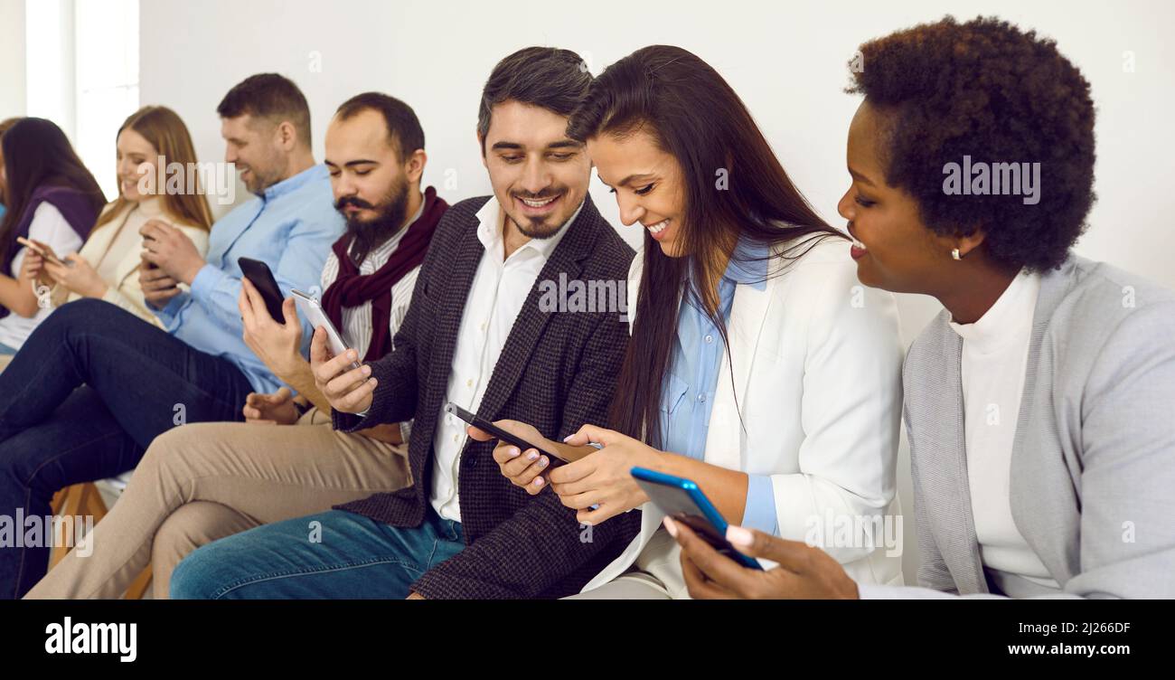 Group of happy diverse friends using mobile phones and sharing a laugh over a funny video Stock Photo
