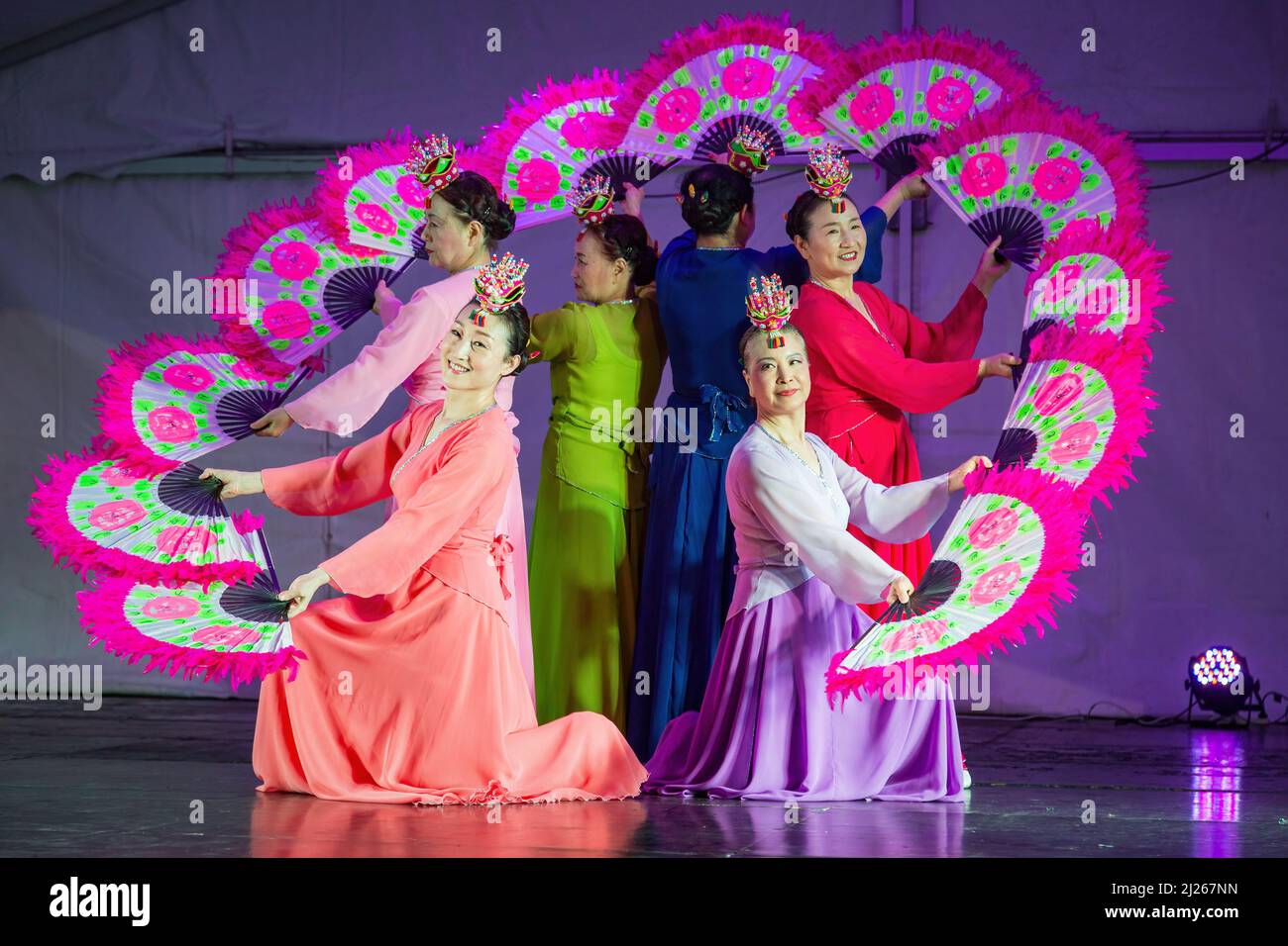 A group of Korean women in hanbok dresses performing a buchaechum, a traditional fan dance Stock Photo
