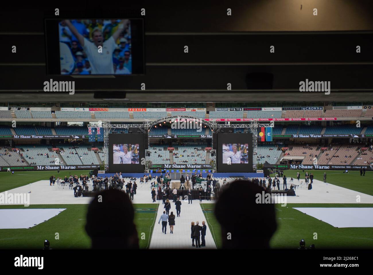 Melbourne, Australia. 30th March 2022. Two fans watch on as Shane Warne highlights play on the screens, before the commencement of the memorial service celebrating Warne's life. Credit: Jay Kogler/Alamy Live News Stock Photo