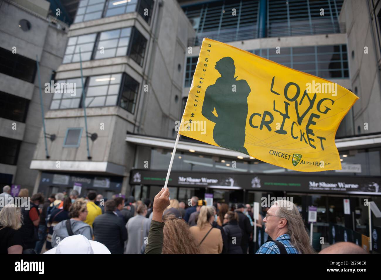 Melbourne, Australia. 30th March 2022. A fan attending the Shane Warne Memorial at the MCG waves a flag reading 'Long Live Cricket'. Credit: Jay Kogler/Alamy Live News Stock Photo