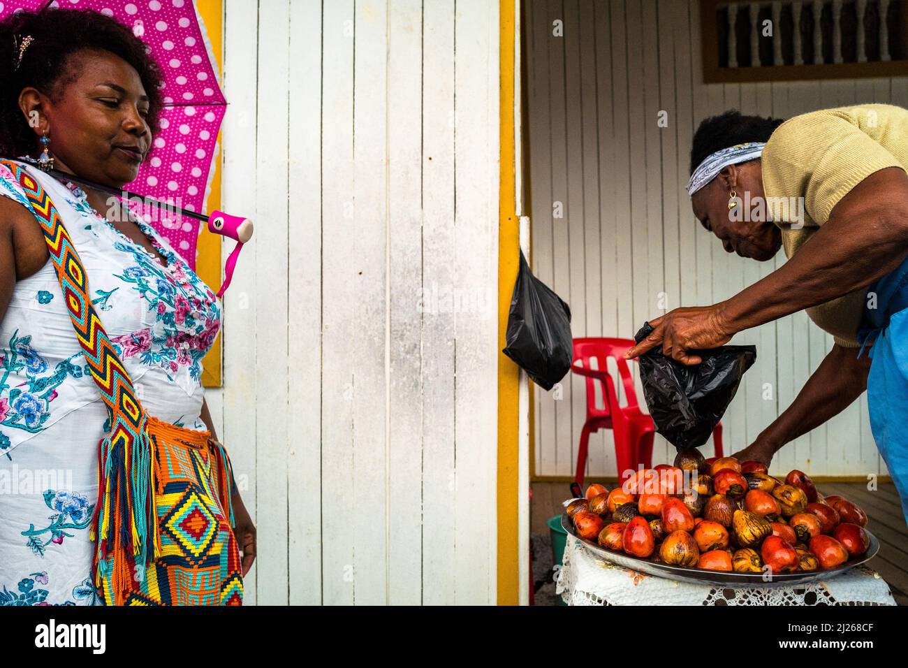 An Afro-Colombian woman sells freshly cooked chontaduro (peach palm) fruits on the porch of her house in Quibdó, Chocó, Colombia. Stock Photo