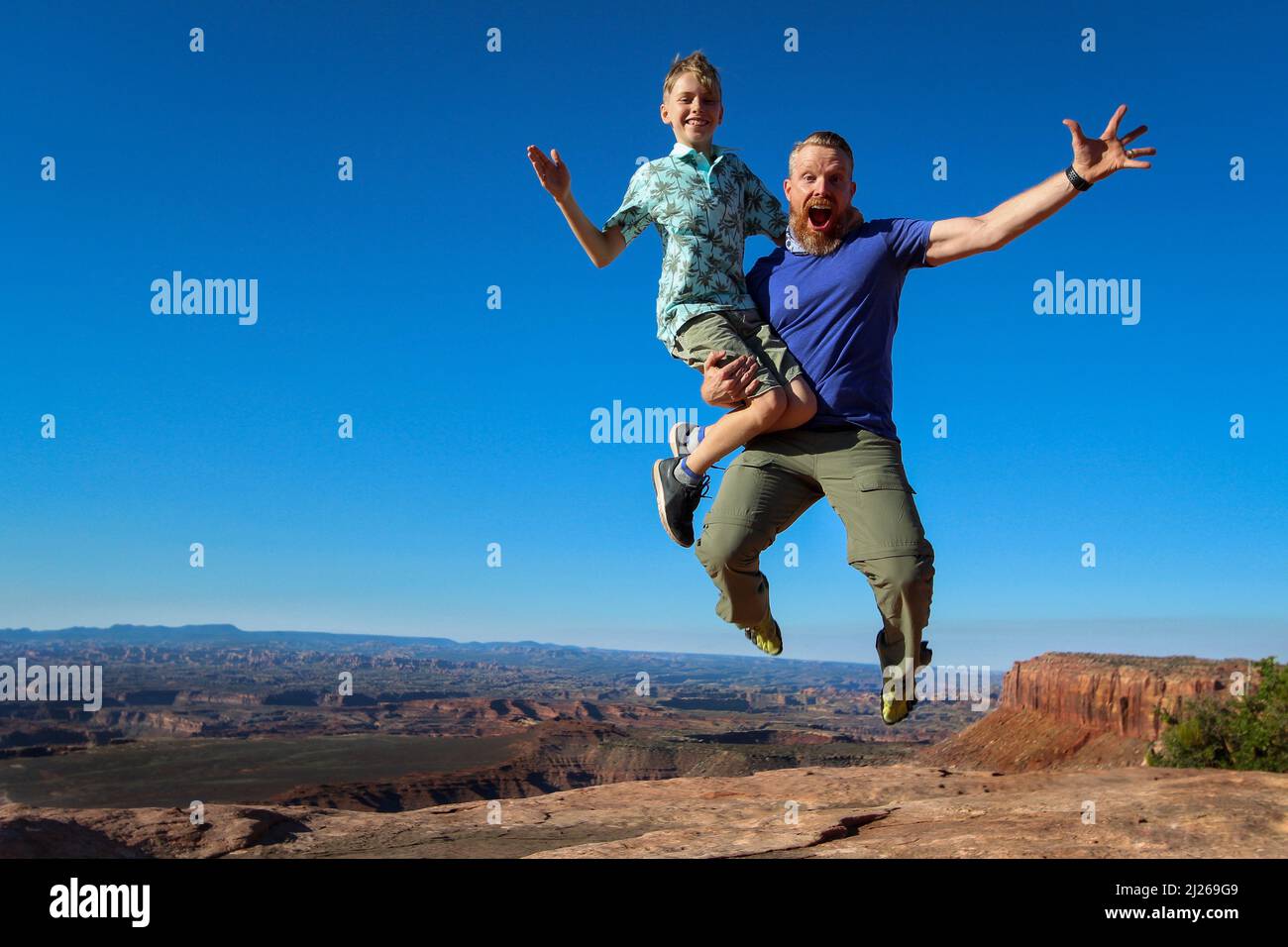A father jumping with his son in his hands in Canyonlands national park ...
