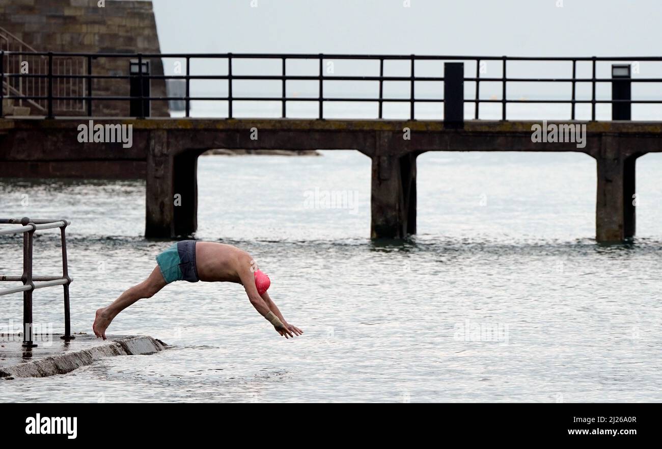A person dives into the sea next to the Hot Walls in Old Portsmouth. Picture date: Wednesday March 30, 2022. Stock Photo