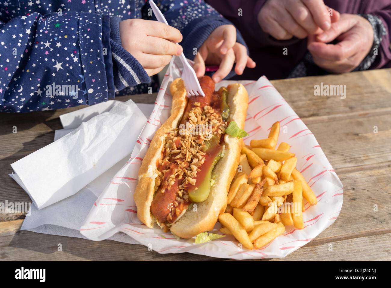 A child eating a hot dog with plate of chips on a day out in Greenwich Southeast London UK Stock Photo