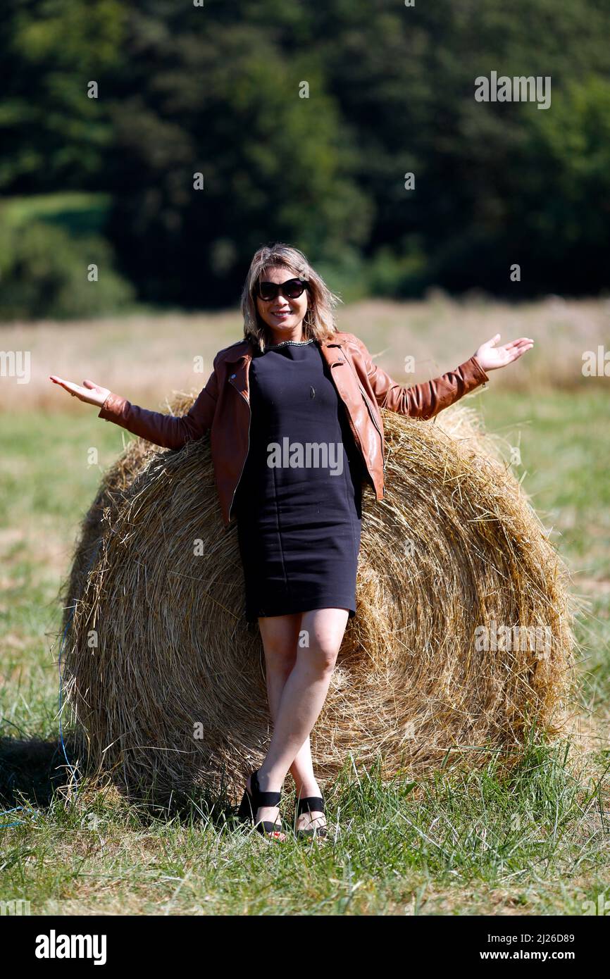 Woman with a roll of straw packed in a freshly cut wheat field. Stock Photo