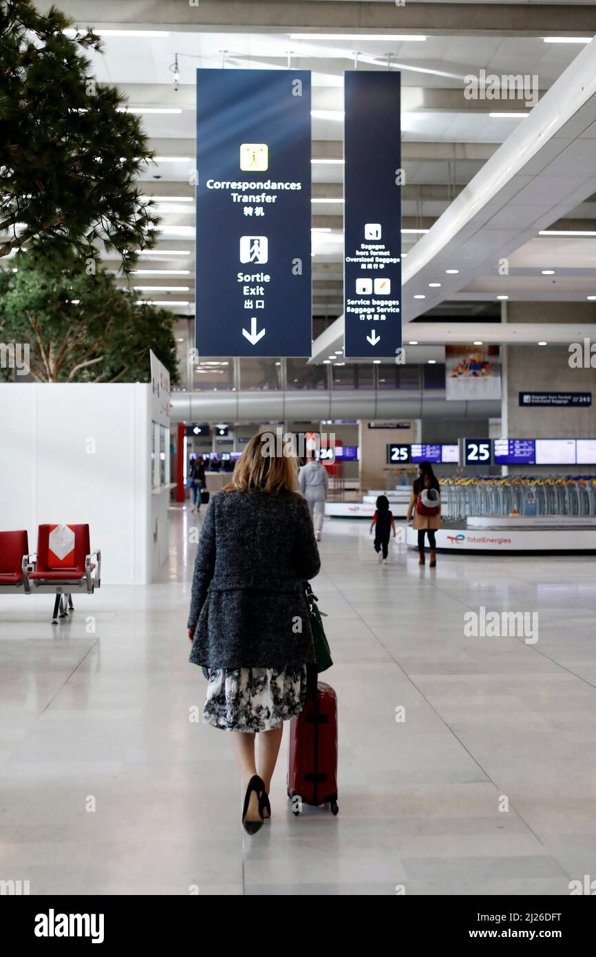 Charles de Gaulle Airport.  Woman travelling with a red suitcase. Stock Photo