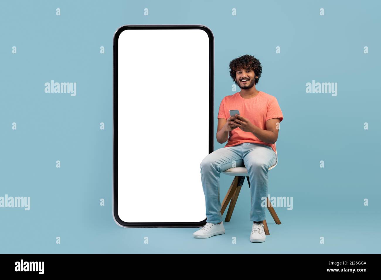 Cheerful curly eastern guy enjoying newest mobile app Stock Photo