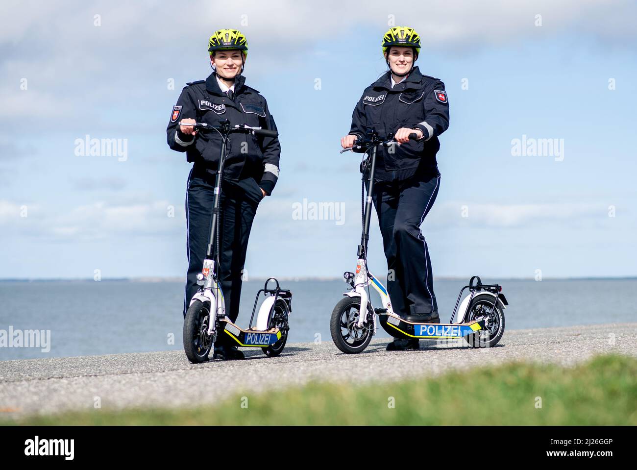Norddeich, Germany. 30th Mar, 2022. Franziska Schrader (l), patrol officer  in Aurich, and Constanze von Garrel, patrol officer in Wittmund, stand on  the dike during a press event with new e-scooters from