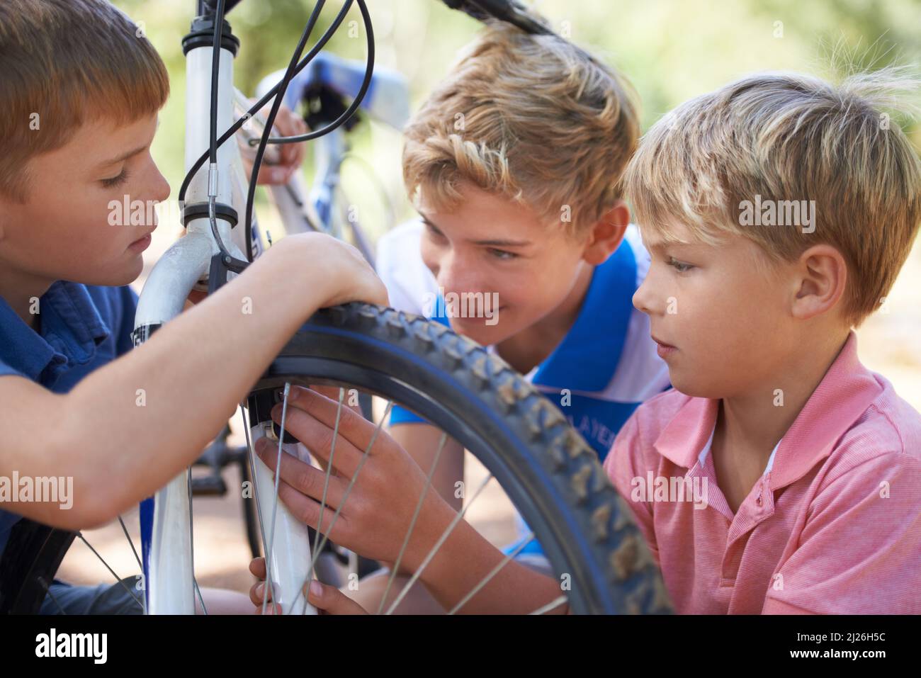 Childhood moments. Happy young boys playing outside with a bicycle. Stock Photo