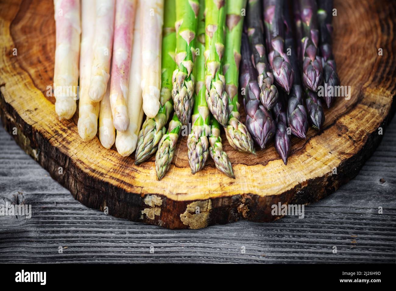 Green, purple and white asparagus sprouts on wooden board closeup. Top view flat lay. Food photography Stock Photo