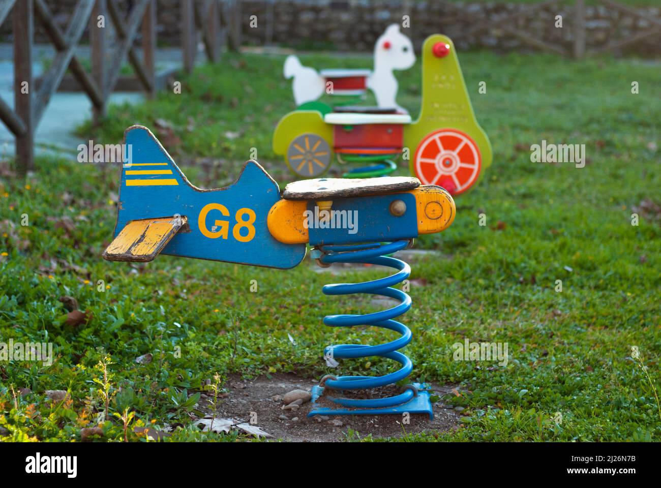 Seesaw swing in the shape of a wooden plane with a spring in a children is playground at sunset Stock Photo