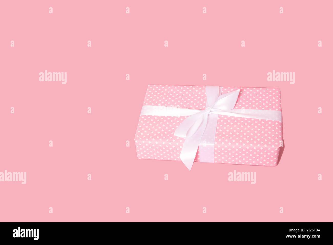 Blank pink pastel color present box with white ribbon isolated over ...