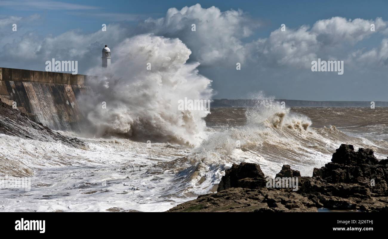 Waves crashing against the Promenade wall and lighthouse at Porthcawl Stock Photo