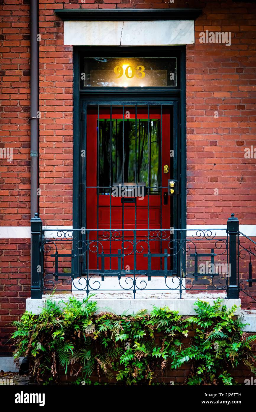 Savannah, Georgia, USA - March 9, 2022. .Red door and black iron gate surrounded by brick in Savannah Georgia, USA Stock Photo