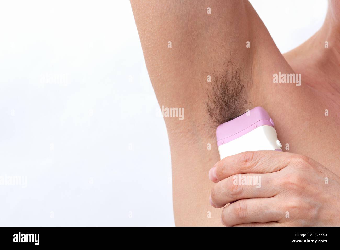 Woman hand removing hair from armpit using electric epilator on white background Stock Photo