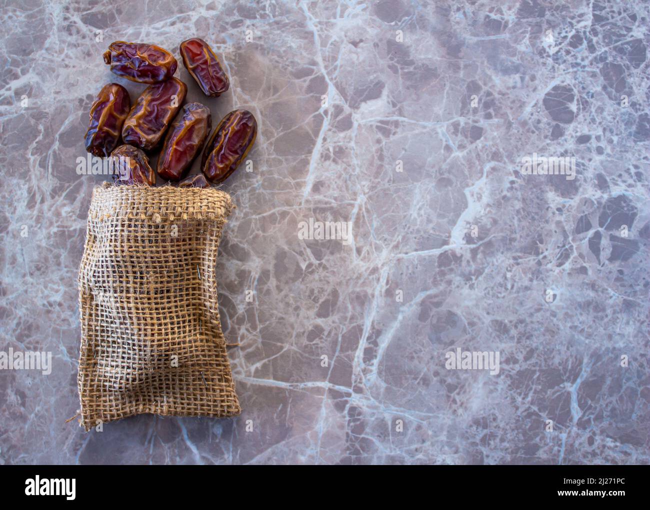 Poured dates top view. Dried date fruits in sack bag on marble