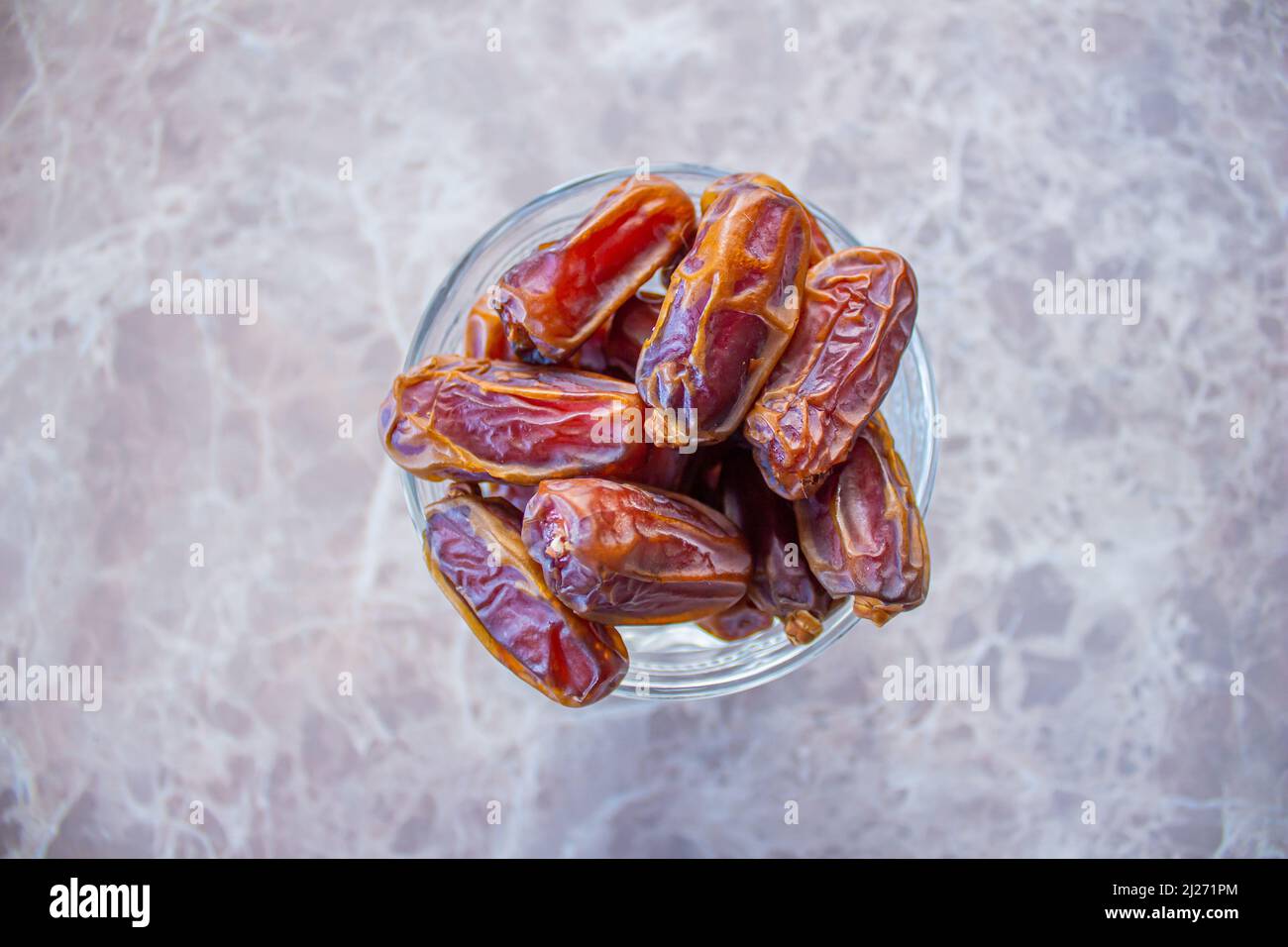 Dried date fruits in bowl on marble background. Top view of ripe dates
