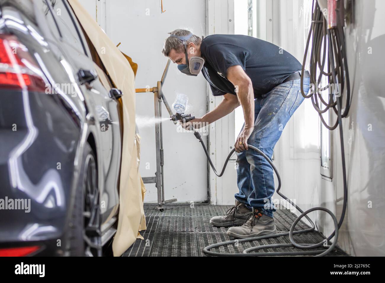 A shallow focus of a man spray painting a car in spraypainting booth