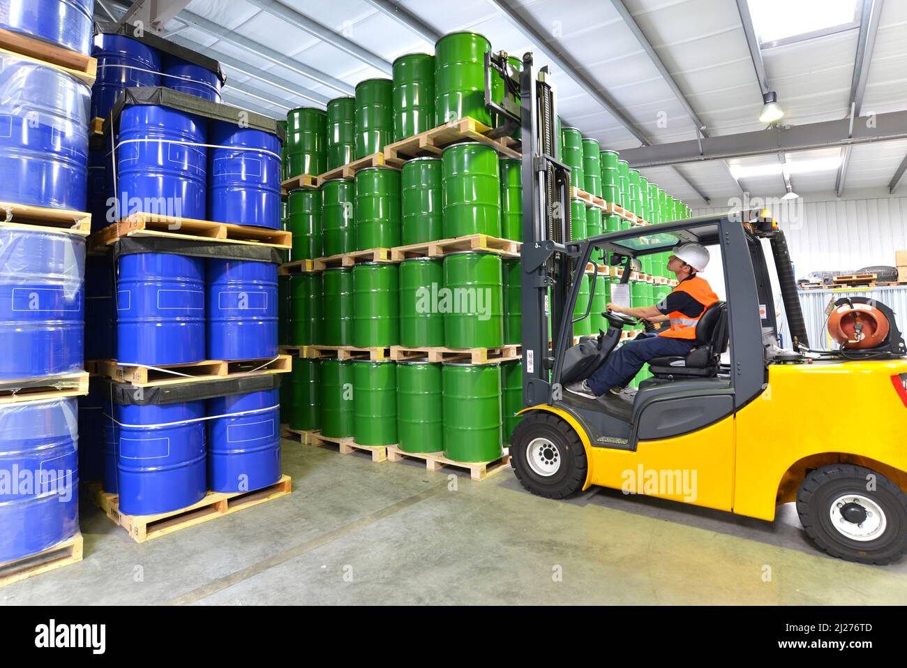 group of workers in the logistics industry work in a warehouse with chemicals - lifting truck Stock Photo