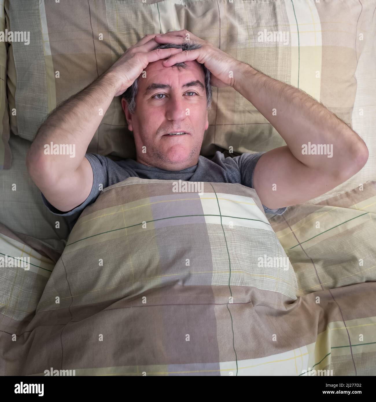 Man with insomnia lying in bed and staring at the ceiling. Stock Photo