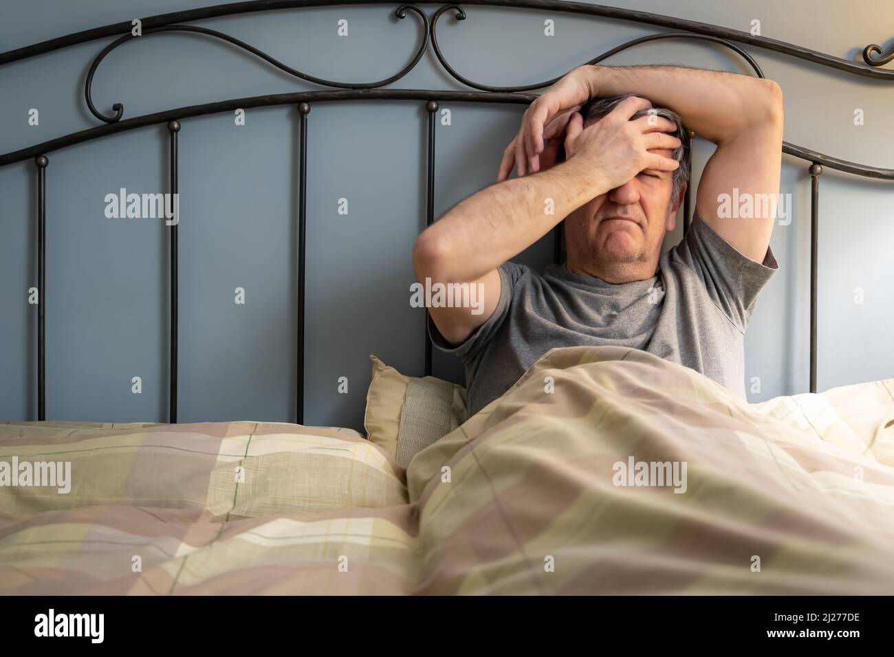 Man with insomnia sitting on the bed and with a gesture of despair. Stock Photo
