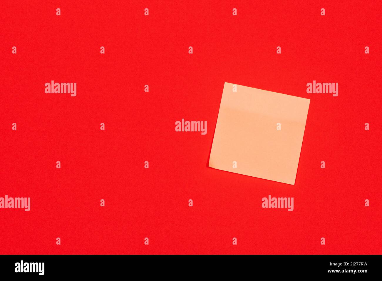 Yellow paper adhesive note stuck to a red background. Stock Photo