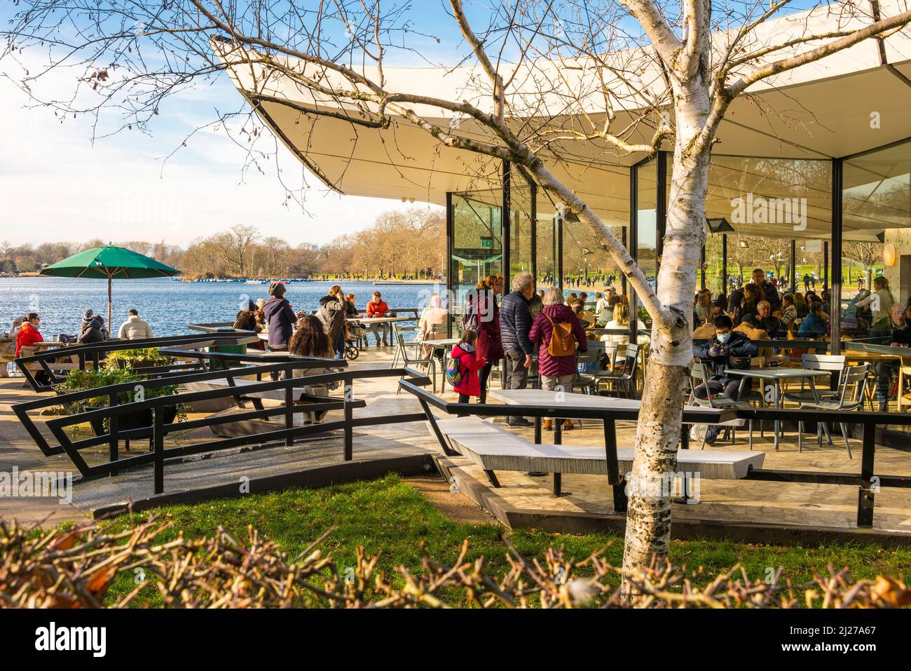 People relaxing and enjoying themselves indoors and outdoors at the Serpentine Bar and Kitchen in Hyde Park, London on a bright sunny winter's day. Stock Photo