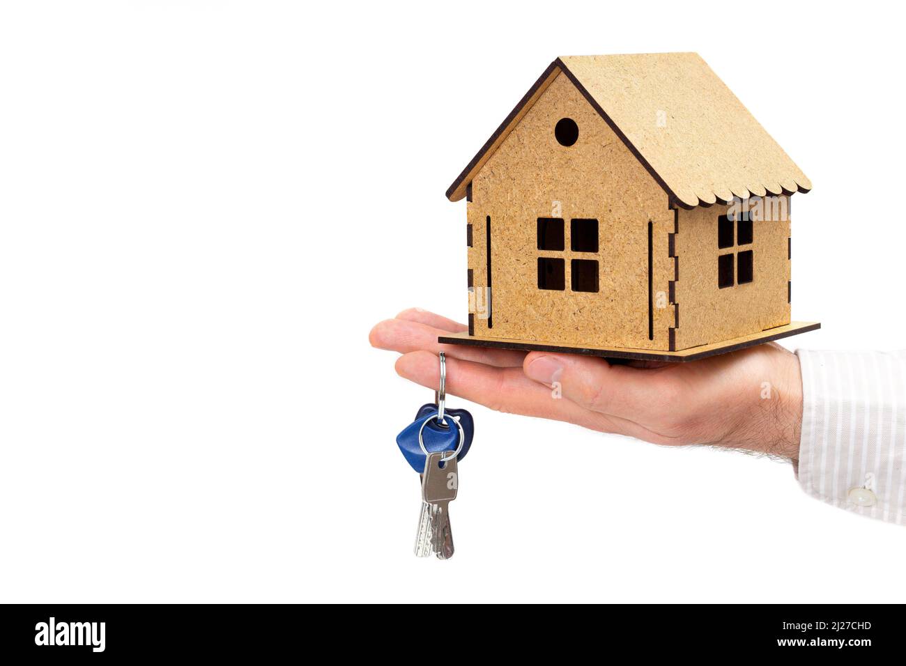 Male hand holding a wooden house model and keys isolated on white ...