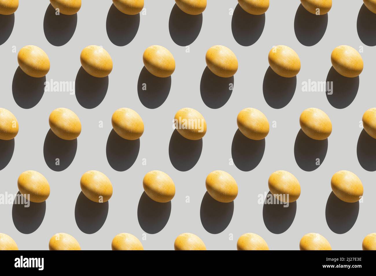 Seamless pattern with Easter eggs, repeating painted yellow eggs with a hard shadow on a gray background, Easter background in pop art style Stock Photo