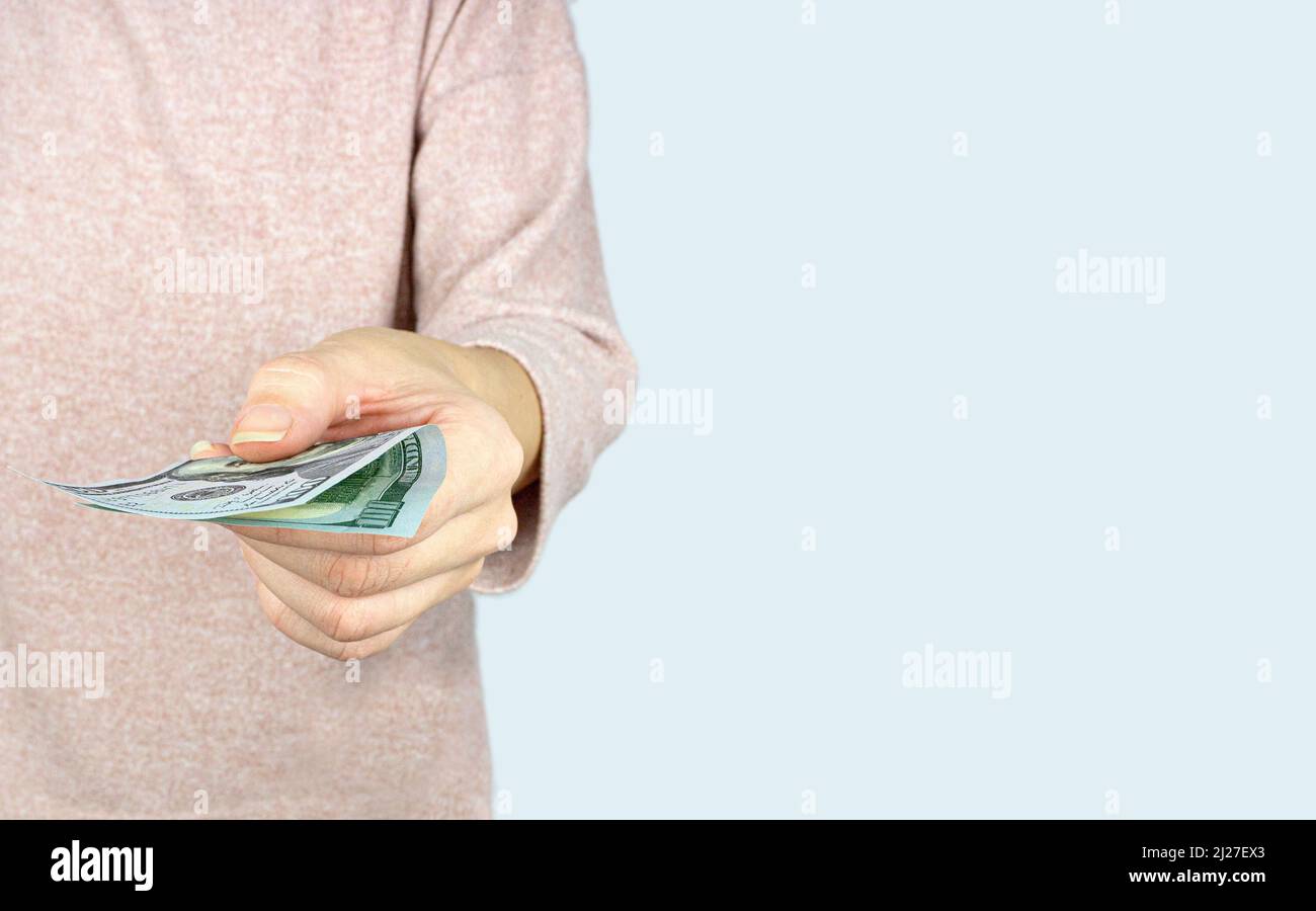 Hand giving money US dollars on grey background, concept of investment, success and profitable Stock Photo