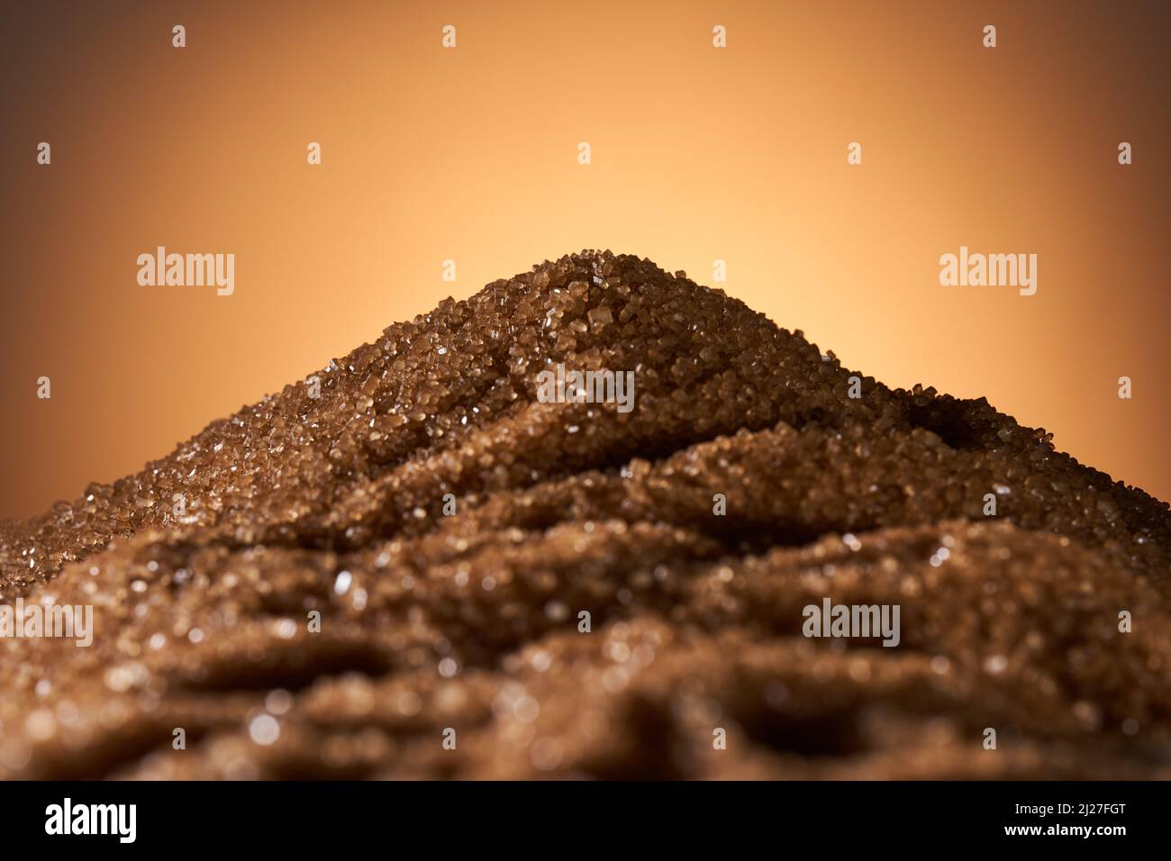 Hills of brown cane sugar, with sunset behind Stock Photo