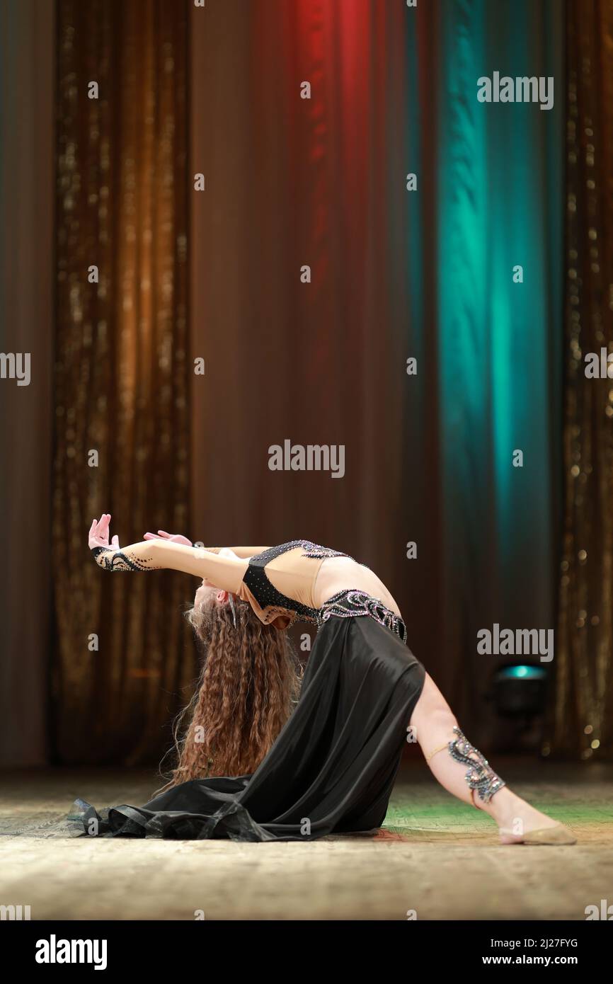 Girls dancers perform on stage with multicolored lights. Backstage