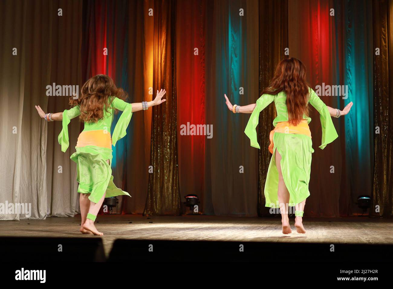Girls dancers perform on stage with multicolored lights. Backstage