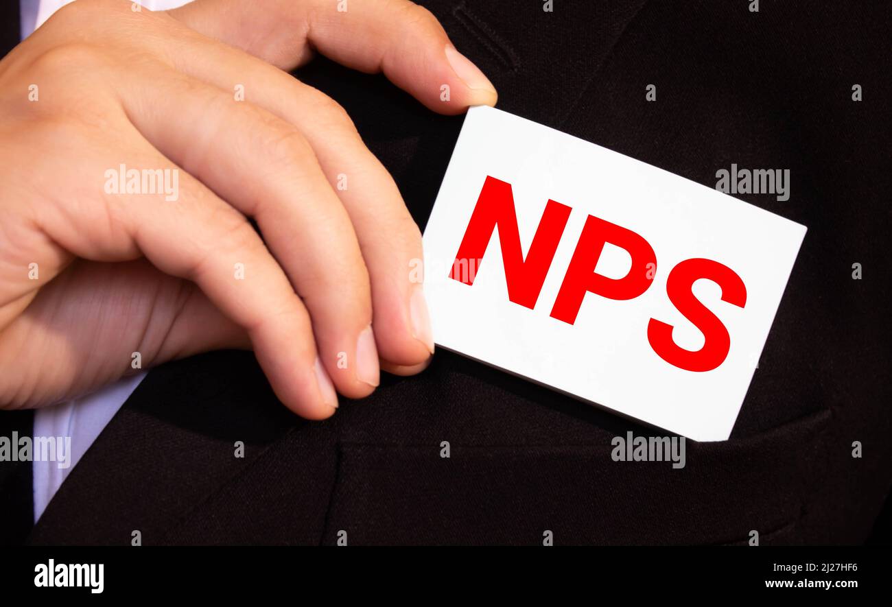 Closeup on businessman holding a card with text NPS NET PROMOTER SCORE, business concept image with soft focus background and vintage tone Stock Photo