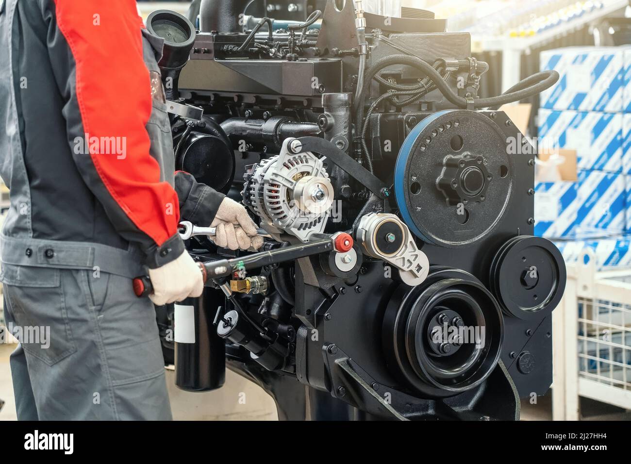 Worker in factory assembles large industrial engine for agricultural machine tractor or combine. Stock Photo