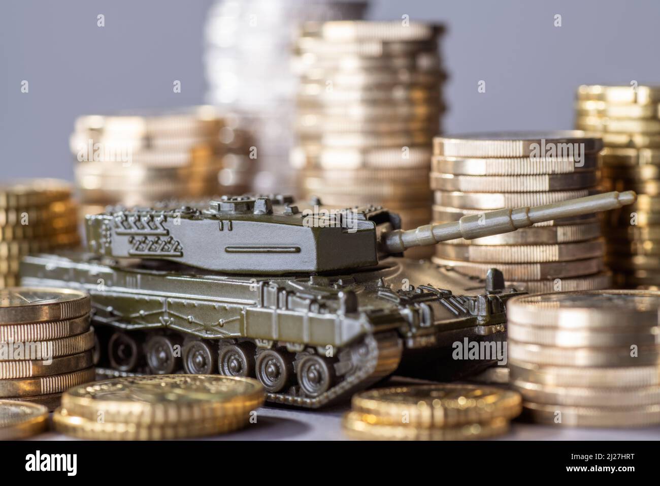 Tank between stacks of coins as a symbol of high armament expenditure Stock Photo