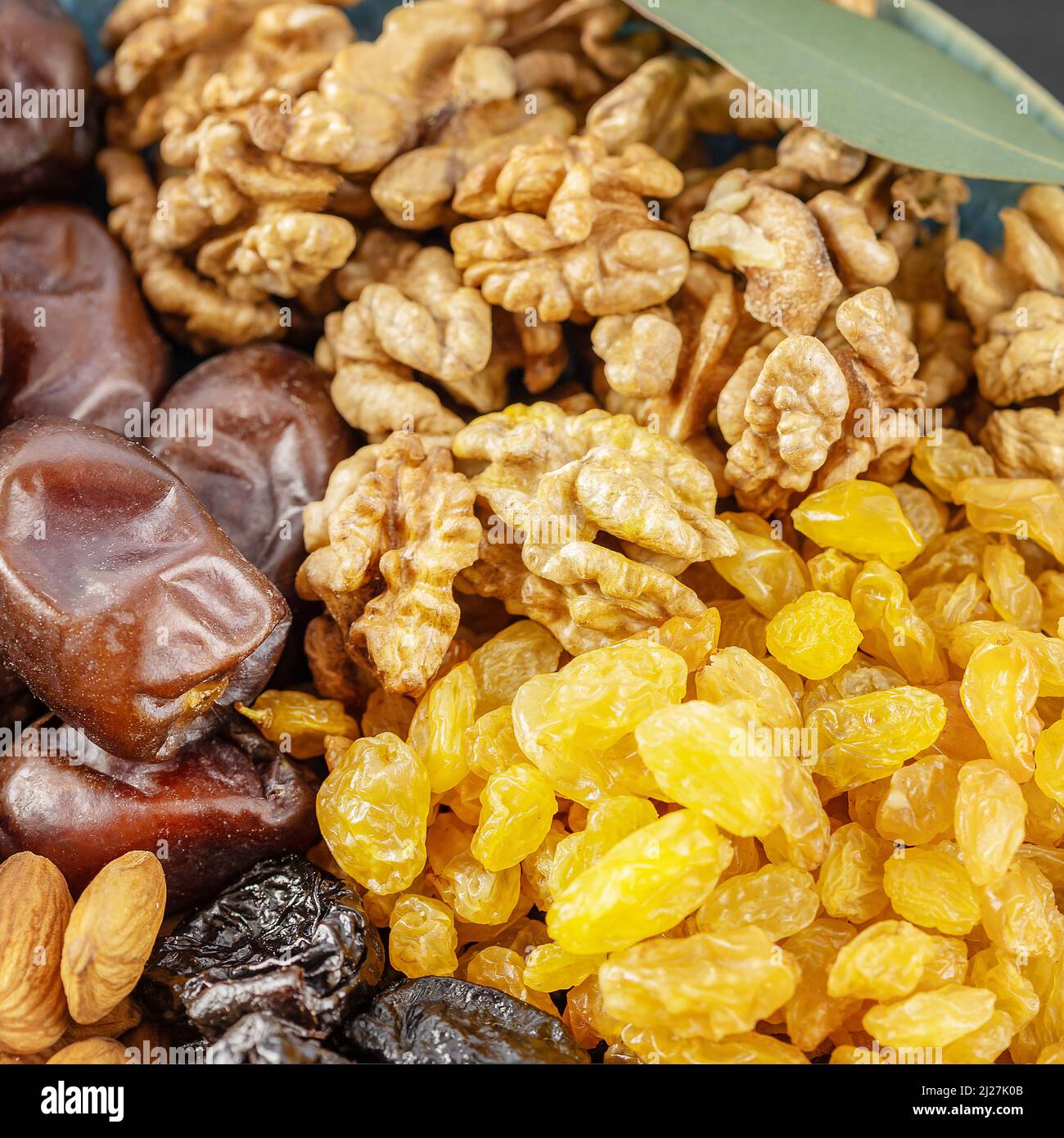 Golden raisins, walnuts, almonds, prunes and dates in the blue bowl on