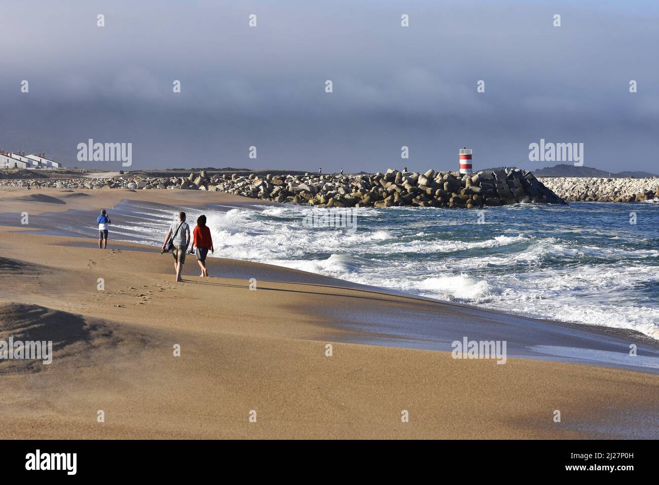 Praia da Nazare, people walking on the sandy beach in the morning, Nazare Portugal. Stock Photo