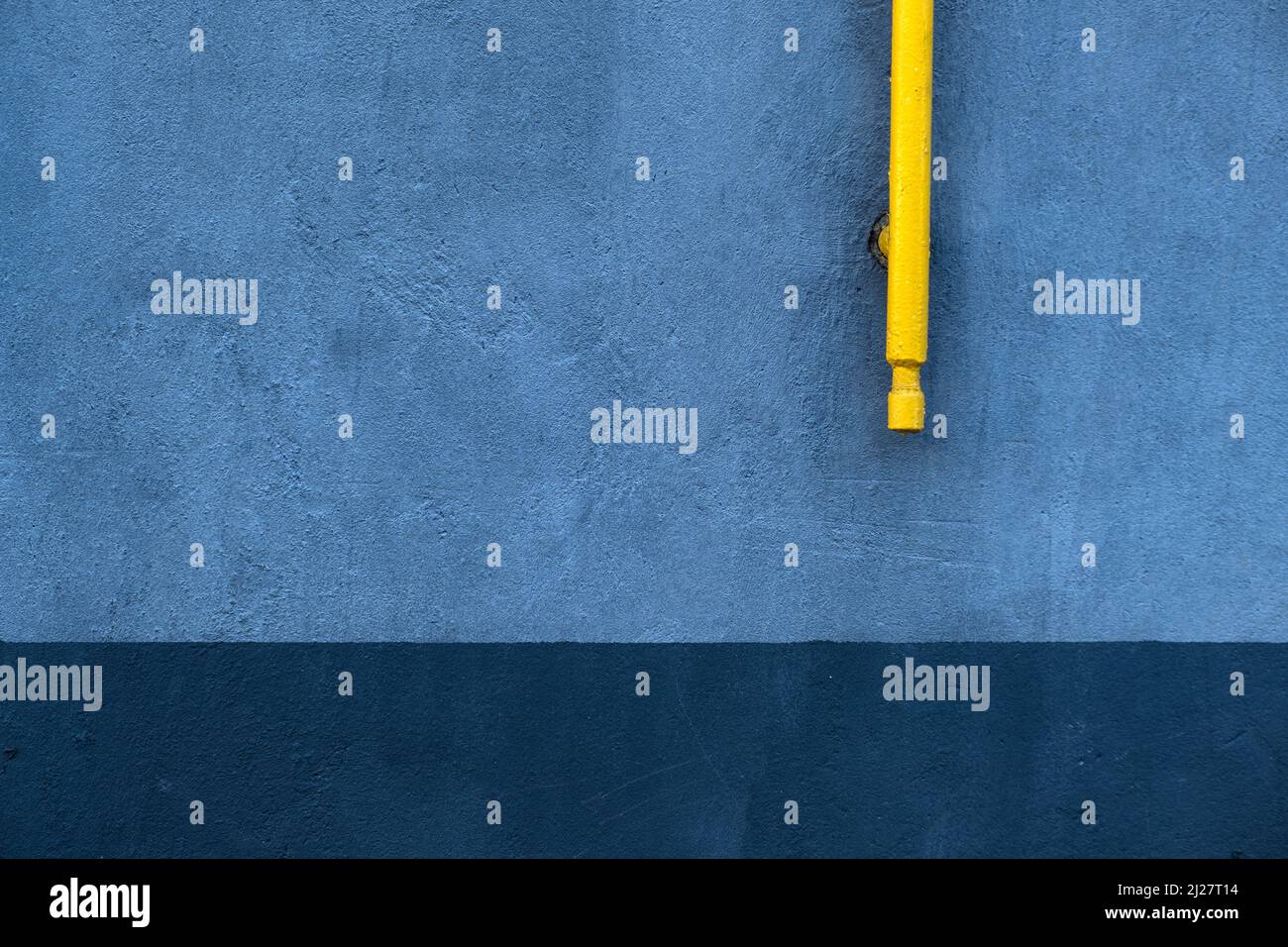 Abstract urban background with blue concrete wall texture and yellow metal pipe Stock Photo