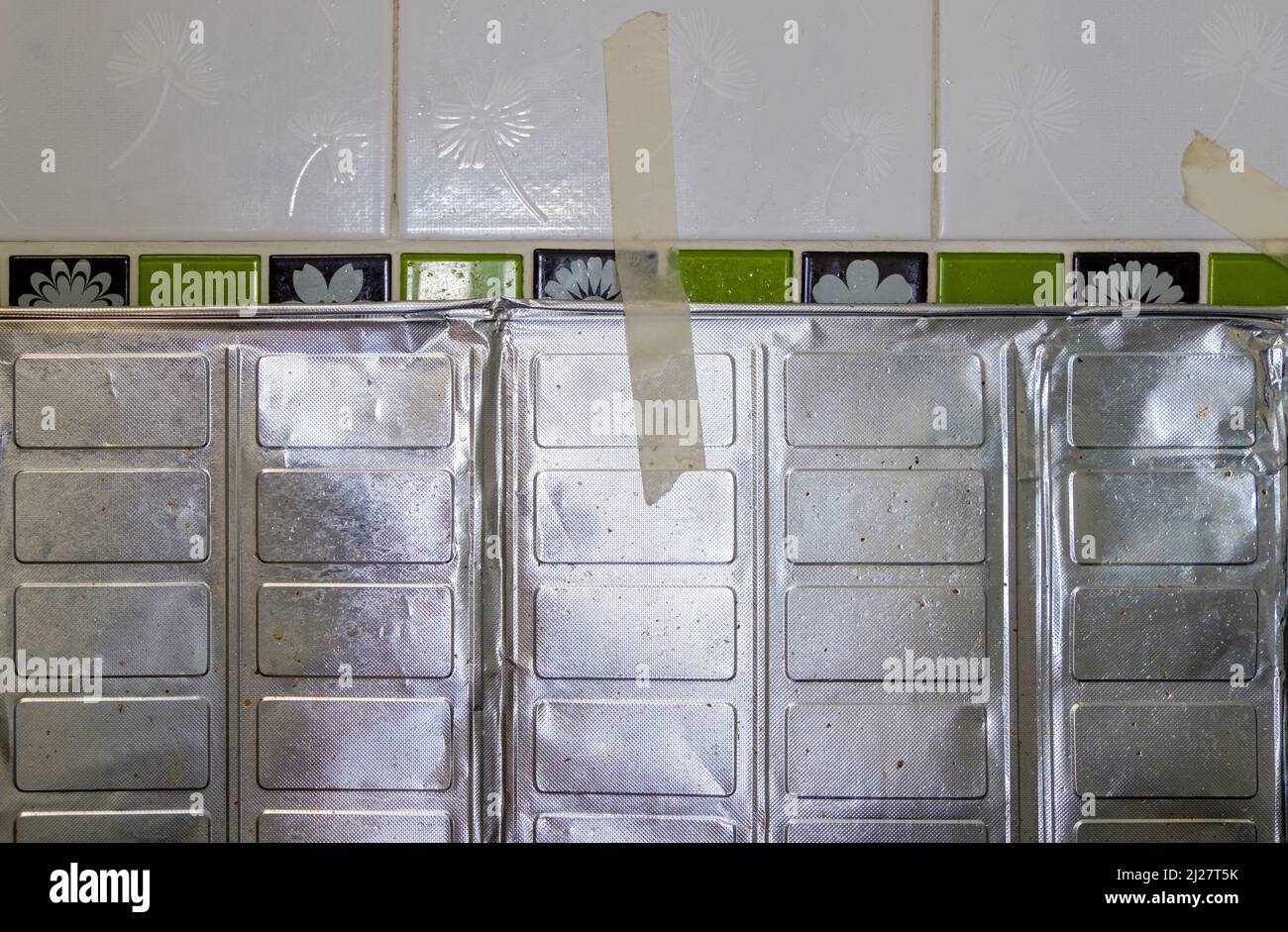 The aluminum sheet for protection of the oil splash from cooking near the gas stove in the urban kitchen, front view with the copy space. Stock Photo