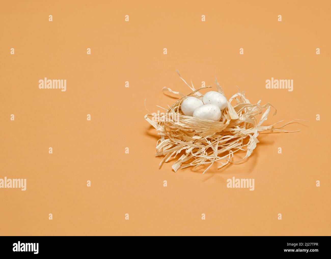 A simple spring concept. Small white eggs in a bright nest Stock Photo