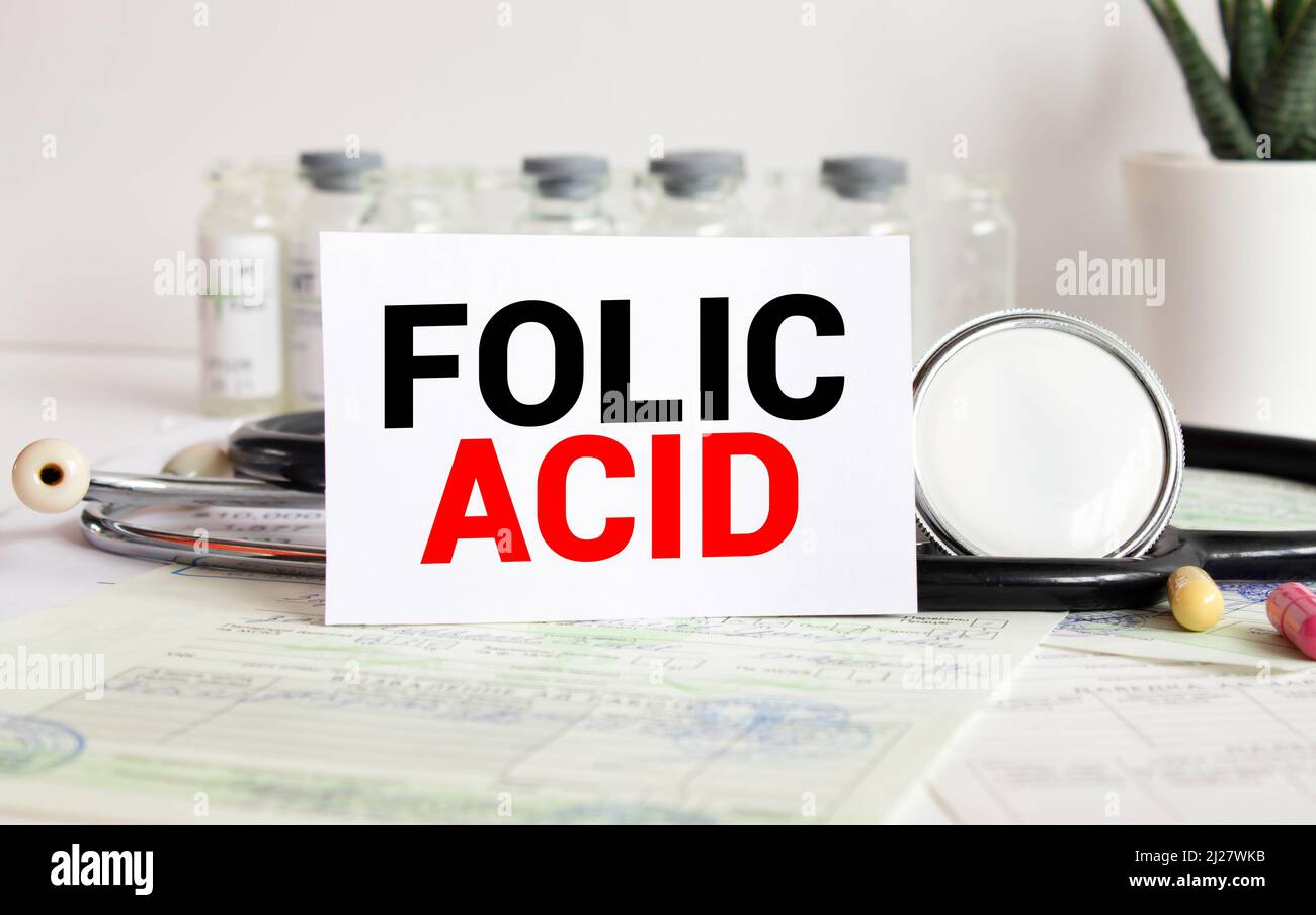 FOLIC ACID text written on card on wooden table with medical background ...