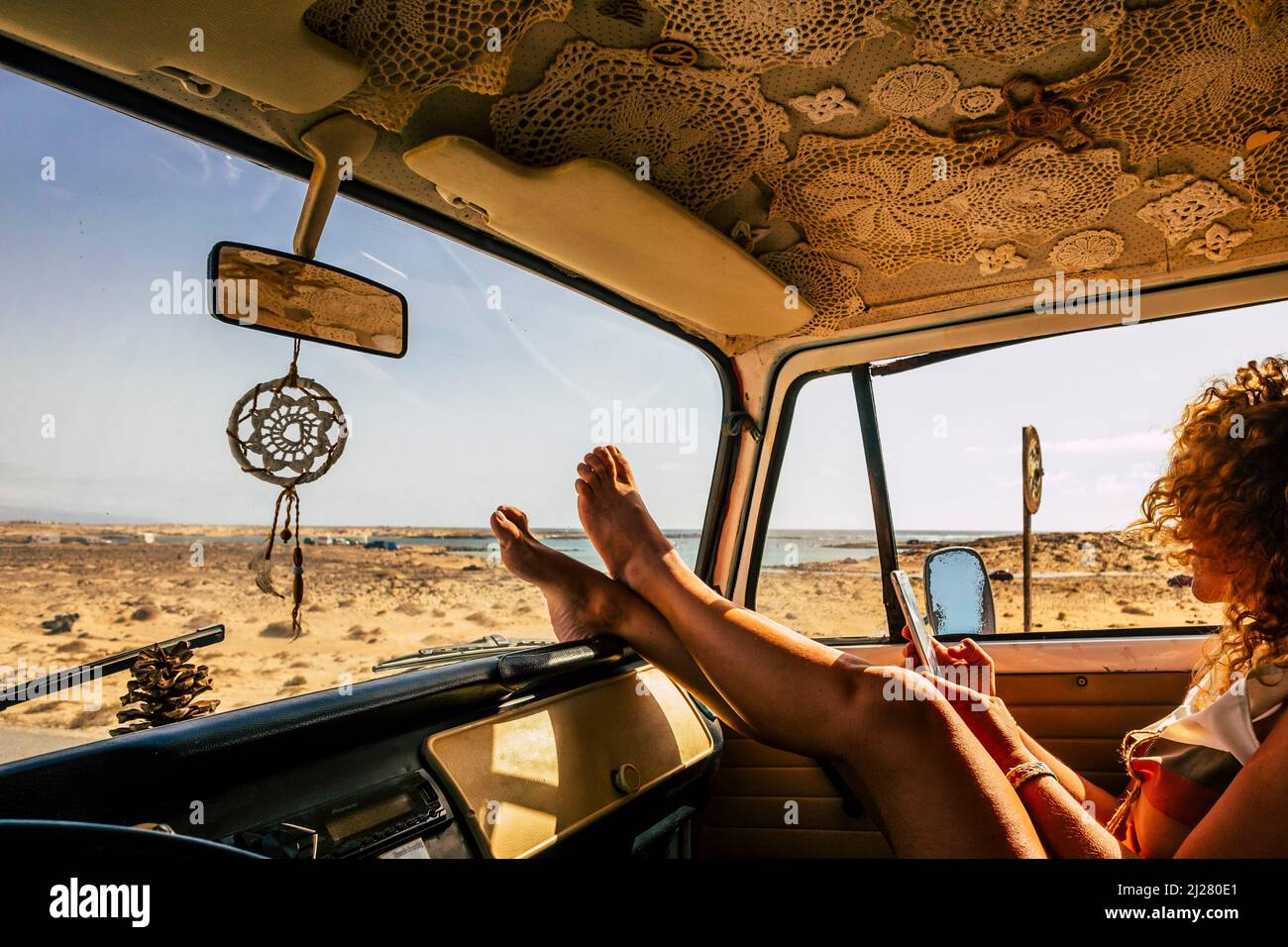 Interior of classic van camper with beautiful legs of woman stretched and relaxed. Travel people lifestyle concept. Summer holiday vacation and vanlif Stock Photo