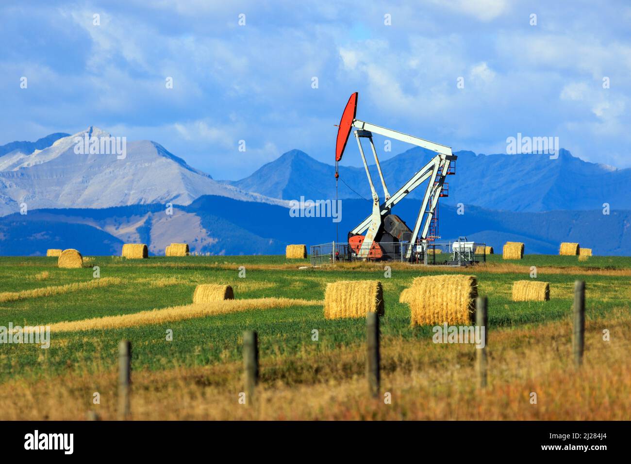 An oil and gas industry pumpjack drill rig in the Canadian Prairies with the Canadian Rockies in Alberta, Canada. Stock Photo
